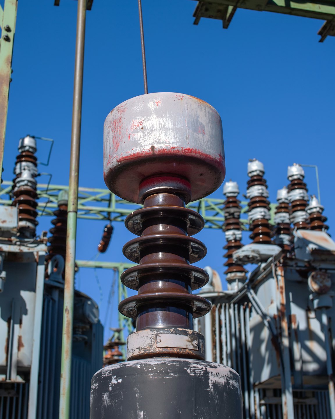 Aislantes de cerámica desgastados y componentes metálicos en una subestación eléctrica.